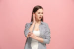 woman with ear pain on pink background.