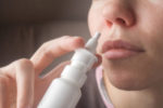 person using nasal spray in nose.