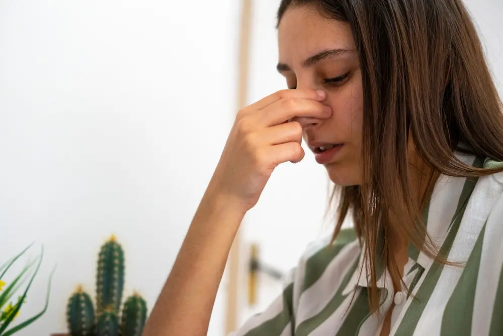 woman holding nose.