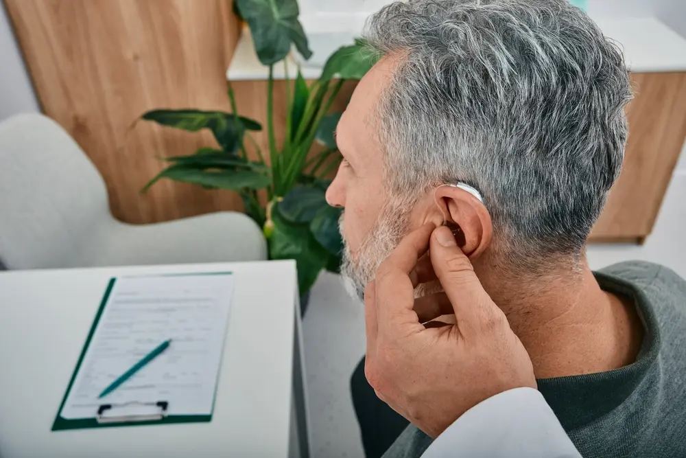 Doctor putting hearing aids in a man's ear.