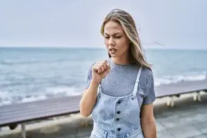 Woman with a sore throat standing on the beach