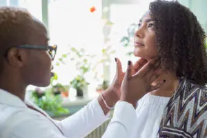 Doctor checking a woman's thyroid glands. 