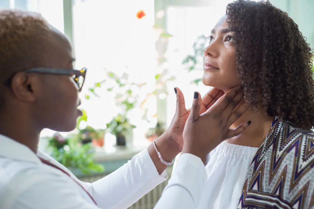 Doctor checking a woman's thyroid glands.