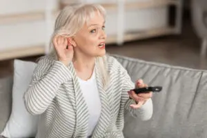 woman struggling to hear the tv.